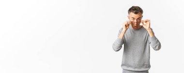 Gri kısa saçlı, yakışıklı ve kendinden emin orta yaşlı bir adamın görüntüsü. Gözlüklerini takmış ve beyaz arka planda duran havalı bir şeye bakıyor..