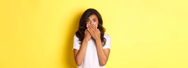 Ürkek ve korkmuş Afro-Amerikan kız portresi, kapa çeneni ve endişeli görün, sarı arka planda korkmuş duruyor..