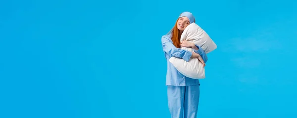 Morning, woman and beauty concept. Full-length vertical shot cheerful, tender, lovely redhead teenage girl in nightwear, sleep mask, close eyes and lean, lying on pillow with closed eyes and smiling.