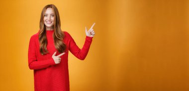 Yaşam tarzı. Arkadaş canlısı görünüşlü, neşeli ve enerjik kızıl saçlı, kırmızı kazaklı kadın sağ üst köşeyi işaret ediyor. Portakala karşı geniş keyifli ve şefkatli bir gülümsemeyle reklamı destekliyor.