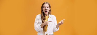 Heyecanlı, nutku tutulmuş, kıvırcık saçlı, ağzı açık, etkileyici genç bir kadının belden yukarısından çekilen görüntüsü hayranlık verici bir şekilde kameraya harika bir fotokopi alanını gösteriyor. Reklamcılık