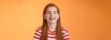 Samimi, mutlu, karizmatik, gülümseyen, kapalı gözlü, yaz güneşinin tadını çıkaran neşeli, rahatlamış hisseden, beyaz dişlerini gösteren, iyi tatil kavramı, turuncu arka plan.