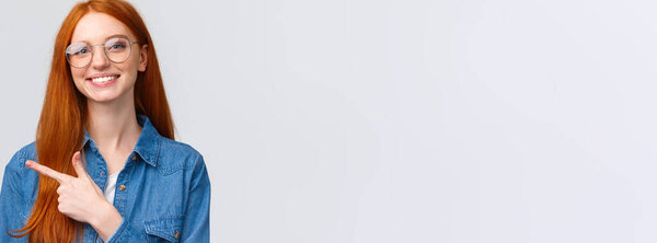 Крупный план Портрет милый веселый рыжий, лисица в очках, показывая место, чтобы нажать на сайт, следить или подписаться, указывая пальцем влево и улыбаясь приятно, с дружественным отношением, белый фон
.