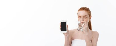 Cep telefonu mesaj yazarken ve okurken ve temiz su içme sağlıklı cilt ile mutlu gülümseyen genç kadın. Diyet danışmanlık. Portre portre.