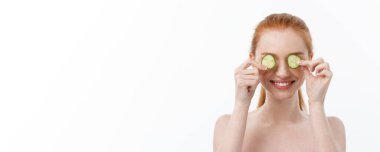 Yüzüne salatalık dilimleri tutan, gülümseyen, yarı çıplak bir kadının güzel portresini kapat. Beyaz arka planda izole edilmiş..