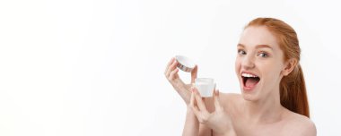 Yüzüne krem sürerken gülümseyen güzel bir kadının portresi. Fotokopi alanı ile izole edilmiş.