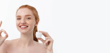 Yüzüne krem sürerken gülümseyen güzel bir kadının portresi. Fotokopi alanı ile izole edilmiş.