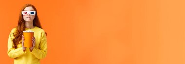 Yaşam tarzı, hobi ve insan konsepti. Üç boyutlu kağıt gözlüklü, elinde patlamış mısır ve ısıran dudak tutan sevimli, inek bir kadın filmde oynayan favori oyuncuya bakıyor, galayı izlemek için sinemayı ziyaret ediyor..