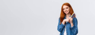 Güzel görünümlü, rüya gibi kızıl saçlı, kot gömlekli, kameralı düşünceli ve görüntülü, bir şeyler çizmek isteyen, aklında tasarım projesi olan, elinde renkli kalemler olan, beyaz arka plan..