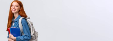 Öğrenciler, eğitim ve öğrenim kavramı. Güzel, karizmatik, kızıl saçlı, sırt çantalı, defterleri ve çalışma kitapları olan, beyaz arka planda duran, gülümseyen, neşeli görünümlü kamerası olan seksi kız..
