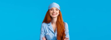 İddialı ve kendine güveni tam iyimser bir kız. Yatmaya hazır, uyku maskesi takmış, gece elbisesi takmış, profesyonel, kendine güvenen bir poz gibi el ele tutuşmuş, mavi arka plan..