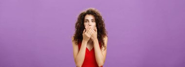 Şok olmuş ve şoke olmuş, kıvırcık saçlı, zarif kırmızı elbiseli, ağzı mor duvarın üzerinde nutku tutulmuş, şaşkınlıktan nefesi kesilmiş, korku ve şaşkınlık içinde bir yetişkin kadın. Boşluğu kopyala