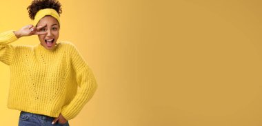 Sarı kazaklı Afro-Amerikan bayan öğrenci zafer jesti gösteriyor. Disko partisinden zevk alarak, neşeyle gülümseyin, neşeyle..