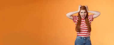 Uneasy depressed fed up pissed redhead girlfriend, scream upset, grab head, pull hair, yelling bothered, pressed, distressed, hate everyone, mental break-down, mind blowing, stand orange background.