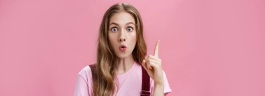 Güzel doğal dalgalı saçlı, yaratıcı duygusal genç bayan öğrencinin Eureka jesti kıvrımlı dudaklarıyla işaret parmağını kaldırırken öneri hayret verici ve heyecan verici derken yakın plan çekimi. Fikirler