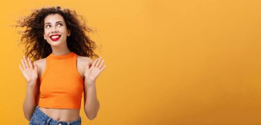 Kaygısız ve mutlu şehir kadını. Burun halkası ve kıvırcık saç stili. Pervasız ve umursamaz bir şekilde avuçlarını kaldırıyor.