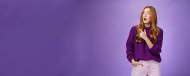 Kız inanılmaz bir sahne görünce şaşırdı ve heyecanlandı. Etkilenmiş ve şok olmuş, mor kazaklı güzel kızıl bir kadının portresi şaşırmış, şaşırmış ve şaşırmış görünüyor..