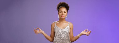Huzurlu, rahatlamış, Afro-Amerikan, zarif gümüş elbiseli, sakin, meditasyon yapan, yakından nefes alan, Nirvana Lotus yogası pozu veren, Zen, mavi arka plan..