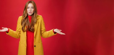 Üzgün ve kafası karışık olan kızıl kız arkadaş ellerini yana doğru uzatarak ne olduğunu anlayamaz ve nedeninin farkında olmadan yüzünü buruşturur, kırmızı duvarın üzerinde endişeli bir şekilde poz verir. Vücut dili ve