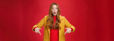 Etkilenmiş kız şaşkınlık ve heyecandan ağzı açık gören kameraya sorgulanan işaret parmaklarıyla soru soran ve kırmızı duvarın üzerinde şaşkına dönen gözlere inanamıyor..