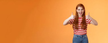 Şımarık asi, vahşi, kızıl saçlı güzel kız eğleniyor harika bir parti veriyor, tatmin edici bir jest sergiliyor, başparmağınla gülümsüyor evet diyor, neşe içinde eğleniyor, eğleniyor, fikir gibi, turuncu arka plan..