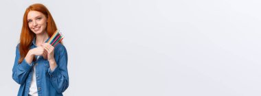 Güzel görünümlü, rüya gibi kızıl saçlı, kot gömlekli, kameralı düşünceli ve görüntülü, bir şeyler çizmek isteyen, aklında tasarım projesi olan, elinde renkli kalemler olan, beyaz arka plan..