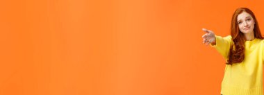 Neşelenmek için sarılmak isteyen bir kız. Sevimli ve dokunaklı kızıl saçlı, sarı kazaklı kadın, kollarını uzat, kucaklaşmak için ellerini uzat, arkadaşına sarıl, gülümse, sevimli, turuncu arka plan.