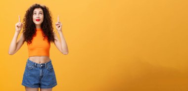 Çekim yapmak isteyen kadın mucizelere inanmaya başlıyor ve umut verici bir şekilde hayal kurmaya ve dua etmeye başlıyor. Turuncu arka planda şık kentsel alanda duruyor. Anlaşıldı.