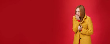 Üşüyen, öksüren, bağıran, soğuk, rüzgarlı havada donan, kamerada rahatsız ve hasta görünen bir kız, kırmızı arka planda grip kaptığını hissediyor. Sağlık ve