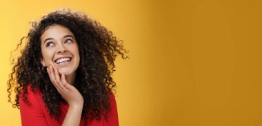 Kırmızı bluzlu mutlu, kıvırcık saçlı, neşeli genç bir kadın. Aptal ve kaygısız bir şekilde gülüyor. Sol üst köşeye bakıyor..