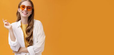 Güneş gözlükleri uyumlu. Kendine güvenen, tasasız, güzel kadın moda blogcusu, gözlüklü, beyaz tişörtlü, el hareketleriyle kameraya gülümseyen kadın portresi..