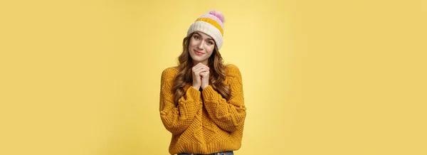 Touched charming cute silly young girl make flirty gazes camera press palms together checking out something moving cute, tilting head seeing adorable kitten, smiling delighted yellow background.