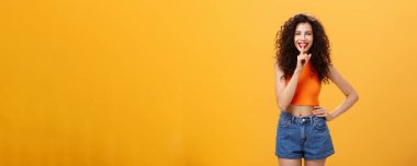 Senin için bir şeyim var. Kıvırcık saçlı, kısa şortlu, etkileyici Avrupalı genç bir kadının portresi. Geniş gülümsemeli, sessiz bir jest yapıyor ve sürpriz hazırlıyor..