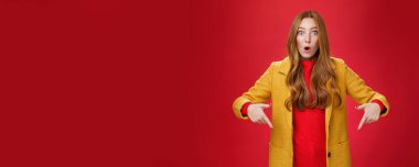 Etkilenmiş kız şaşkınlık ve heyecandan ağzı açık gören kameraya sorgulanan işaret parmaklarıyla soru soran ve kırmızı duvarın üzerinde şaşkına dönen gözlere inanamıyor..