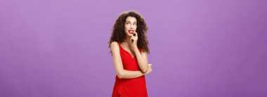 Aptal ve ürkek çekici kadın. Koyu kıvırcık saçlı, şık bir gece elbisesi ve kırmızı ruj ısıran parmağıyla sağ üst köşede sevimli görünüyor. Düşünceli bir görüntü ya da arzu edilen bir şeyin hayalini kuruyor..