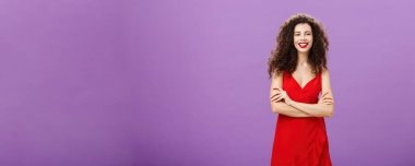 Şirin, hırslı ve mutlu Avrupalı bir kadın. Gösterişli kırmızı elbisesiyle kendinden emin bir şekilde el ele tutuşarak mezuniyeti mor arka planda kutlarken gülümsüyor..