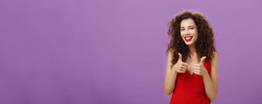 Destekleyici kız arkadaş, erkek arkadaşının taşınmasına onay veriyor. Kıvırcık saçlı, kırmızı elbiseli, cana yakın, çekici bir kadın. Mor arka planda onaylıyor ve gülümsüyor..