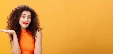 Özür dilerim. Habersiz ve cahil, aptal, çekici bir kadın. Kıvırcık saç stili omuz silkiyor, belirsiz sırıtıyor. El hareketlerini kim bilebilir ki?.