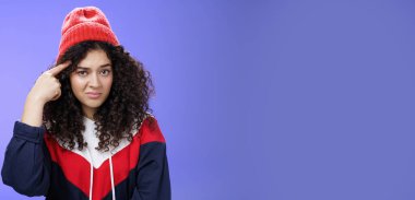 Lifestyle. Close-up shot of confused and annoyed woman being shocked with weird and stupid behaviour rolling index finger over temple and looking questioned at camera as wonder of dumb friend ideas.