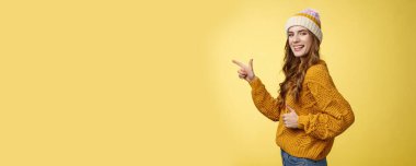 Yaşam tarzı. Profil çekimi karizmatik flört güzel görünümlü genç kız kamerayı sola çevir işaret parmağı göster baş parmaklarını göster jest gibi harika bir yeri tavsiye eden sarı arka plan.