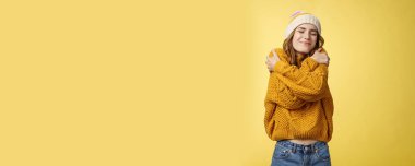 Neşeli, neşeli, neşeli genç bir kadın kendini şanslı hissediyor. Yeni, rahat bir süveter gibi kendini kucaklıyor. Başı öne eğik..