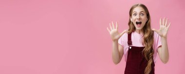 Kablo yok. Heyecanlı ve şaşkın, yakışıklı, karizmatik, doğal saçlı, kablosuz kulaklık takan ve pembe duvardan neşeyle gülümseyen boş ellerini gösteren beyaz kadın.