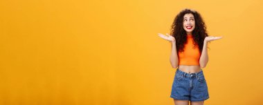 Aptal ve cahil, tatlı kız. Kıvırcık saçlı, kıvırcık saçlı ve kısa şortlu, avuçlarını yana açıp gülümseyerek sağ üst köşeye bakıyor. Belirsiz ve ilgisiz..