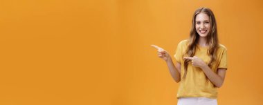 Kız ziyaret etmek için güzel bir yer gösteriyor. Tasasız, sevimli, doğal, dalgalı saçları işaret eden, işaret parmaklarıyla solu gösteren ve reklam için harika bir yer olan büyüleyici genç bayan portresi..