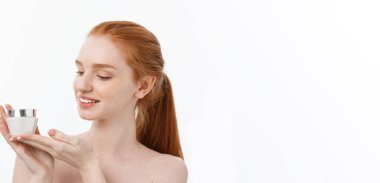 Yüzüne krem sürerken gülümseyen güzel bir kadının portresi. Fotokopi alanı ile izole edilmiş.