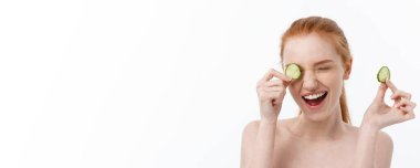 Yüzüne salatalık dilimleri tutan, gülümseyen, yarı çıplak bir kadının güzel portresini kapat. Beyaz arka planda izole edilmiş..