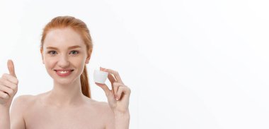 Yüzüne krem sürerken gülümseyen güzel bir kadının portresi. Fotokopi alanı ile izole edilmiş.