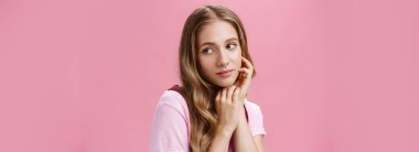 Rüya gibi şehvetli ve kadınsı, doğal saçları dalgalı ve hassas görünüşlü genç bir kadın cilt bakımı ve kozmetik tedavisinden sonra kendini güzel ve narin hisseder ve nazikçe yanağa bakar.