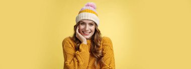 Yumuşak, romantik, güzel görünümlü, kalın şapkalı, örgü ören, gülümseyen, flört eden, seni baştan çıkaran, mutlu görünen, yalın kafalı, meraklı, sarı arka planlı bir kadın..