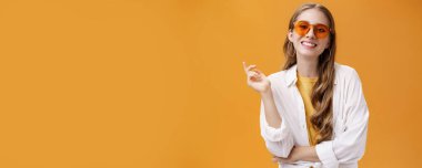 Güneş gözlükleri uyumlu. Kendine güvenen, tasasız, güzel kadın moda blogcusu, gözlüklü, beyaz tişörtlü, el hareketleriyle kameraya gülümseyen kadın portresi..